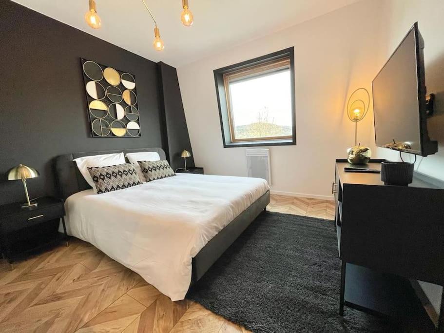 a bedroom with a large white bed and a television at Studio Esplanade bord du Lac in Aix-les-Bains