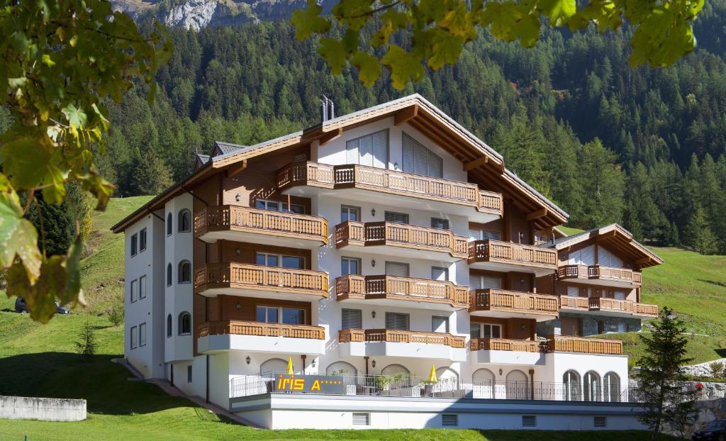 um grande edifício de apartamentos com varandas numa colina em Apartments Residenz Iris em Leukerbad