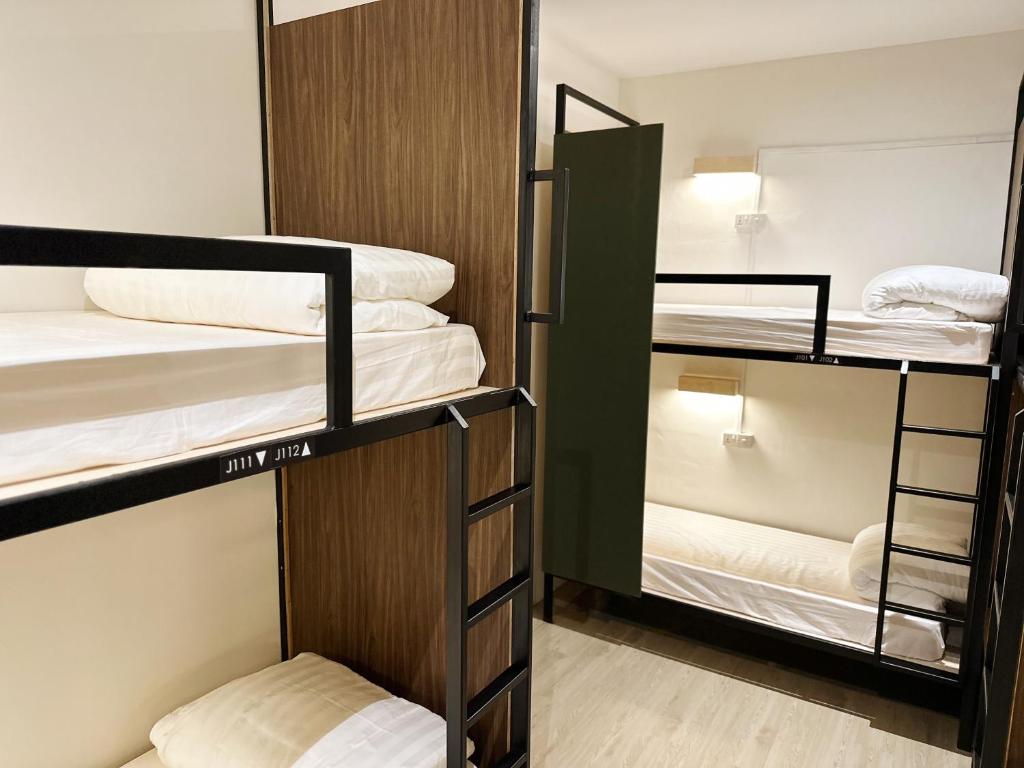 a room with three bunk beds in a dorm room at Jiran Hostel Kota Kinabalu in Kota Kinabalu