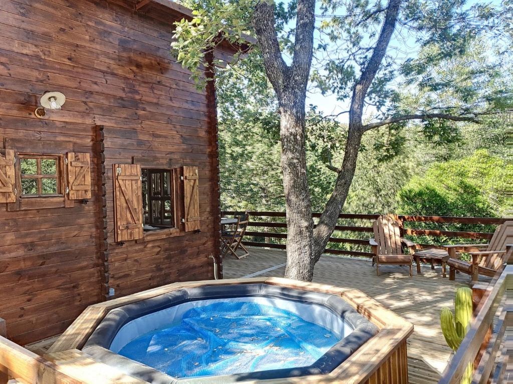 a hot tub on a deck next to a tree at Chalets du golfe de st Tropez l olivier in La Garde-Freinet