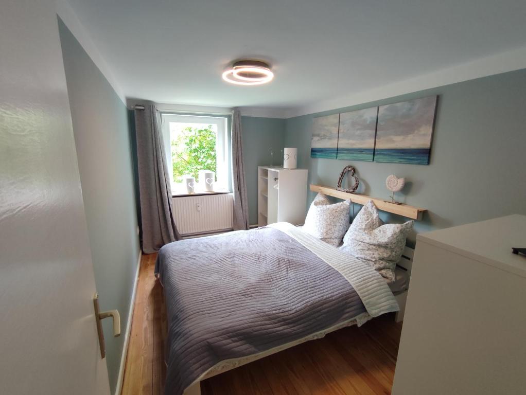 um quarto com uma cama com lençóis brancos e uma janela em Ferienhaus Hygge em Flensburg