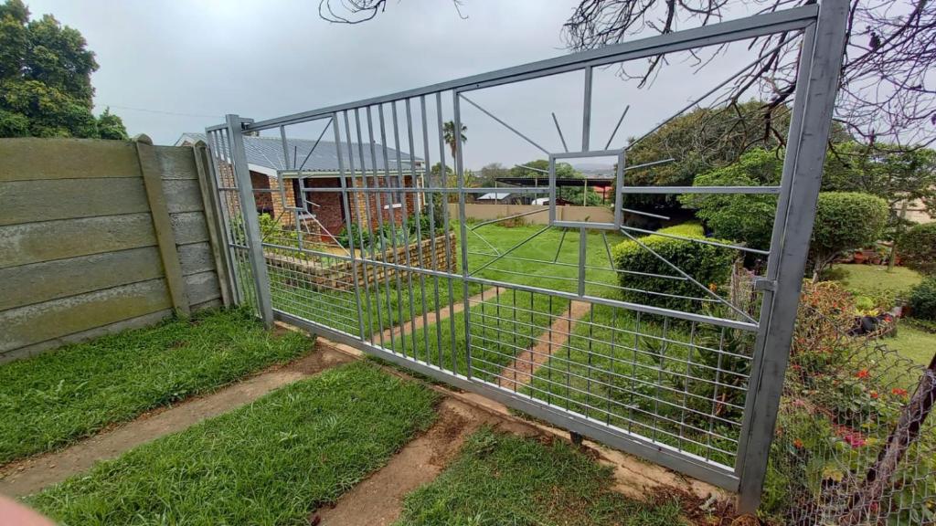 a gate in a yard with a garden at Hidden Cottage in Bredasdorp