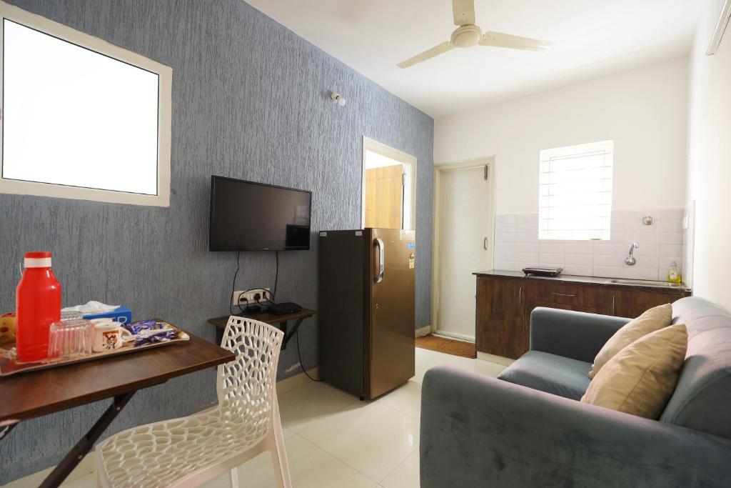 a living room with a couch and a table and a refrigerator at StayhomeStays Prime in Bangalore
