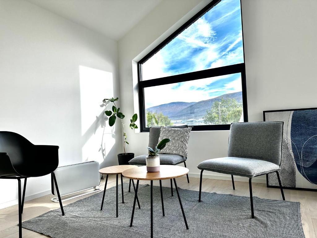 Tromsø central guest house with parking في ترومسو: غرفة معيشة مع كراسي وطاولة ونافذة كبيرة