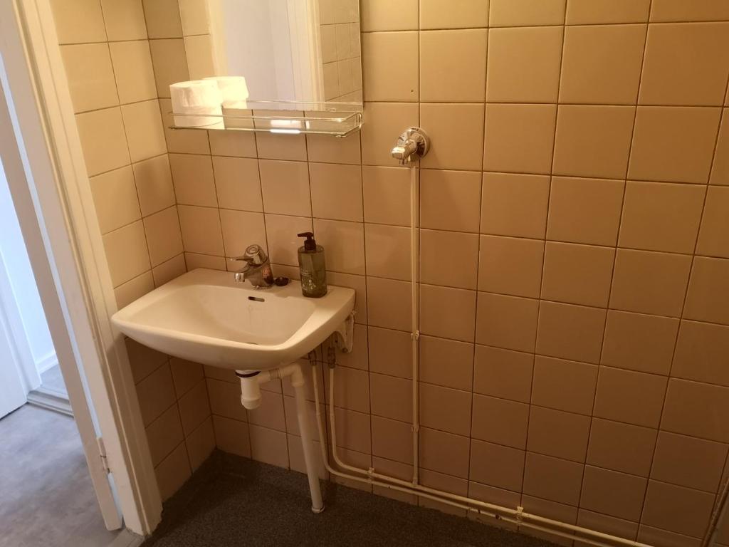 baño con lavabo y pared de azulejos en Kontiomäen retrokoti, en Kontiomäki