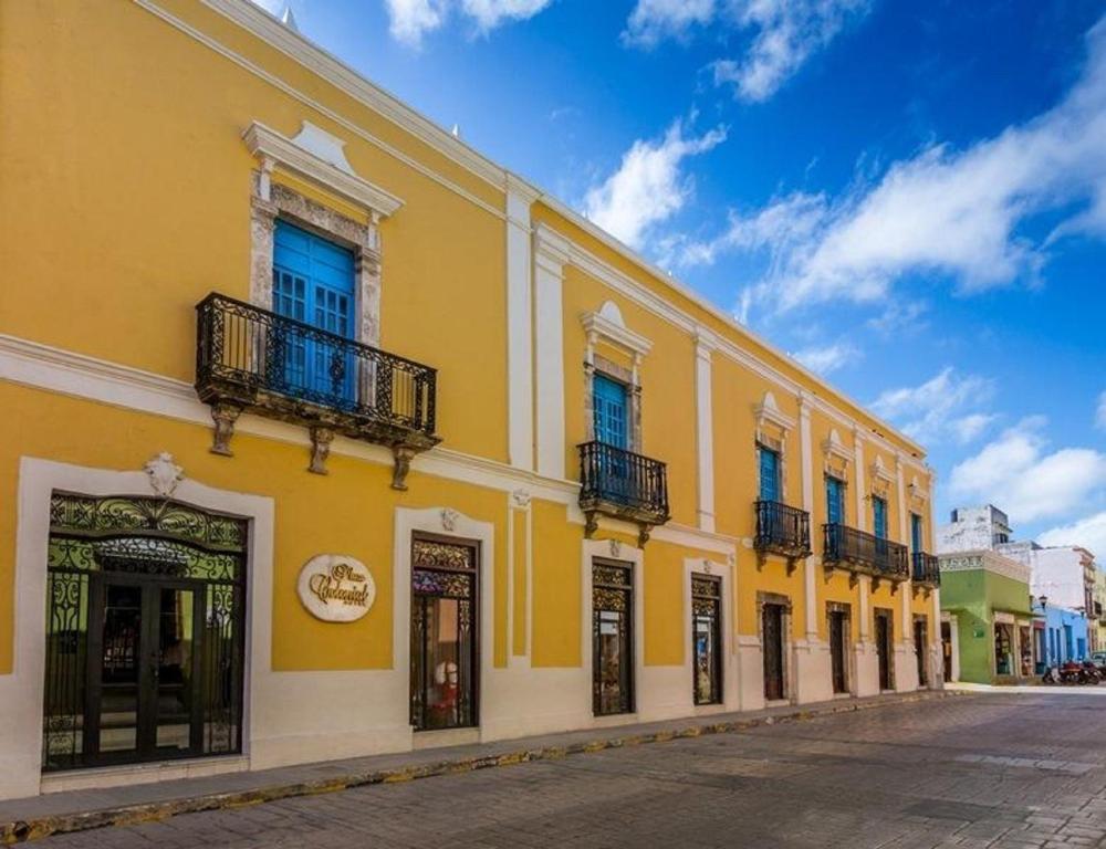 a yellow building with windows and balconies on a street at Hotel Plaza Colonial in Campeche