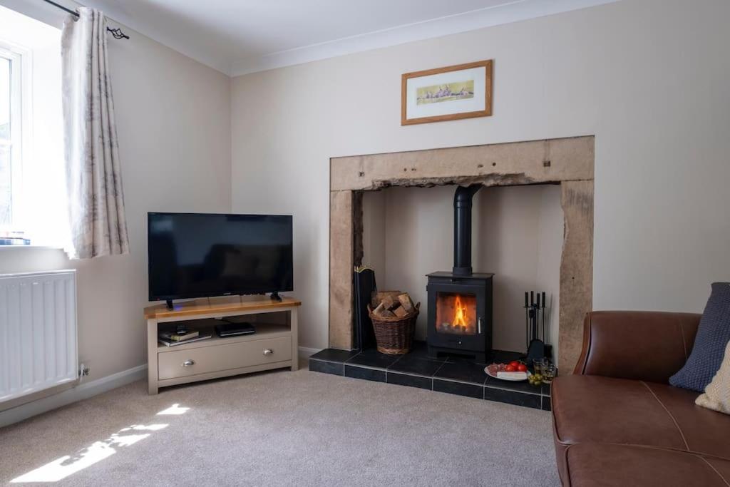 a living room with a fireplace and a tv at Cosy Northumbrian Cottage in Barrasford