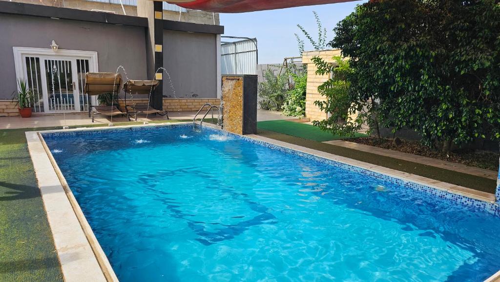 a large blue swimming pool in front of a house at merana charlet in Ash Shāghūr