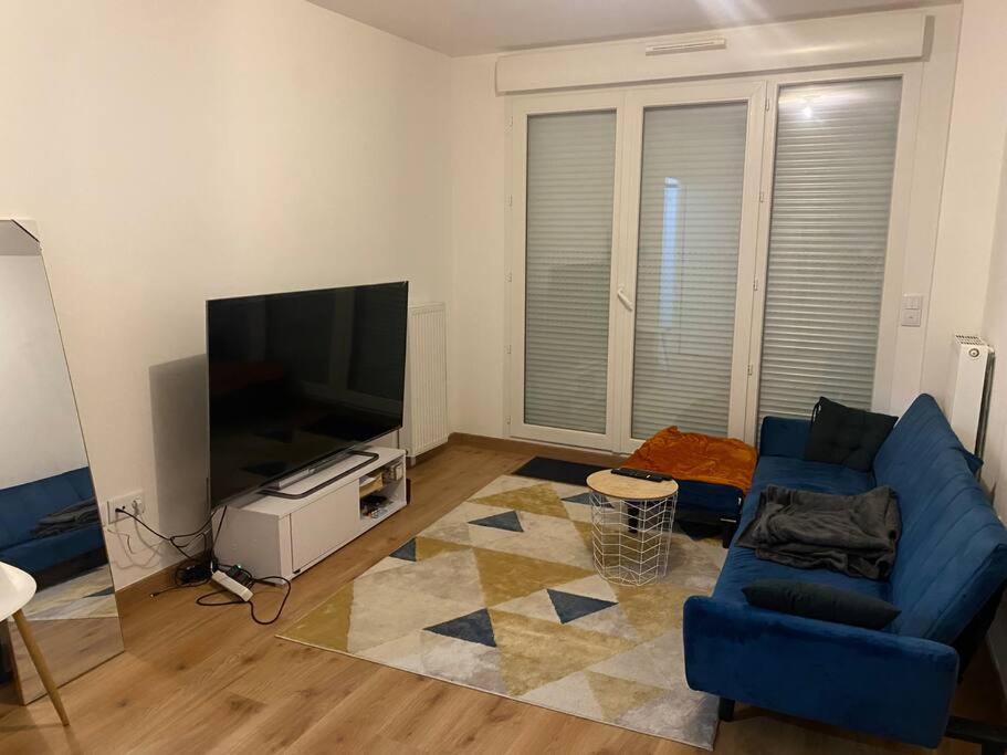 uma sala de estar com um sofá azul e uma televisão de ecrã plano em Chez Ivy-Guizela em Saint-Maur-des-Fossés