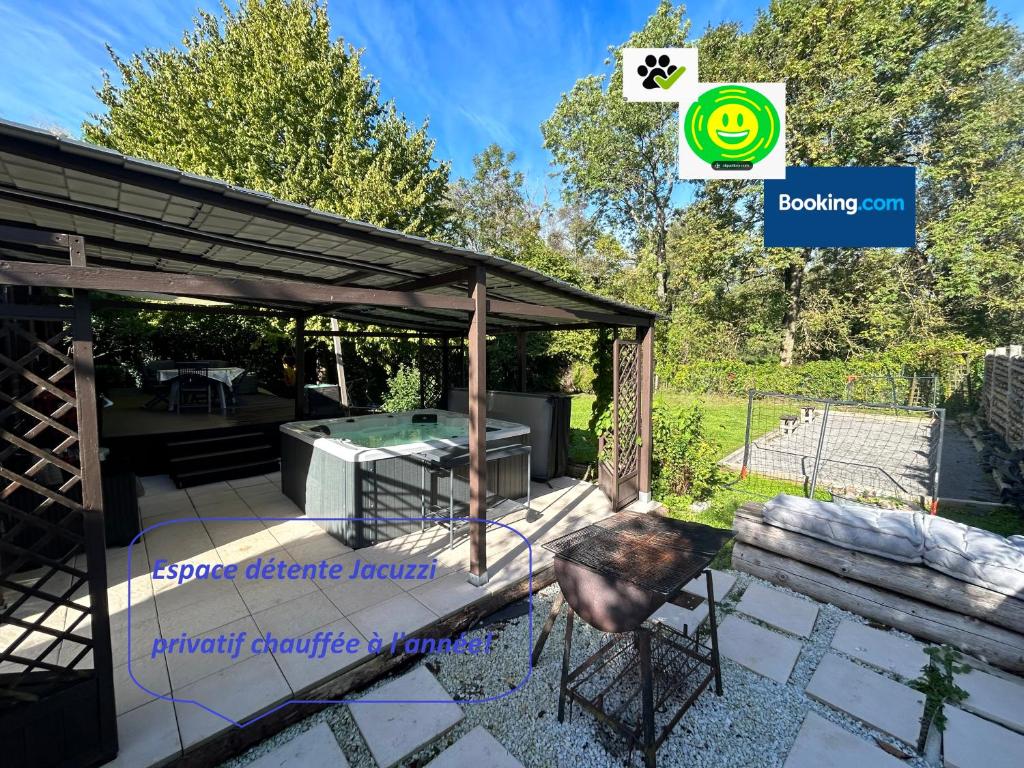 eine überdachte Terrasse mit einem Grill und einem Tisch in der Unterkunft Cottage tres bien équipé avec jacuzzi 