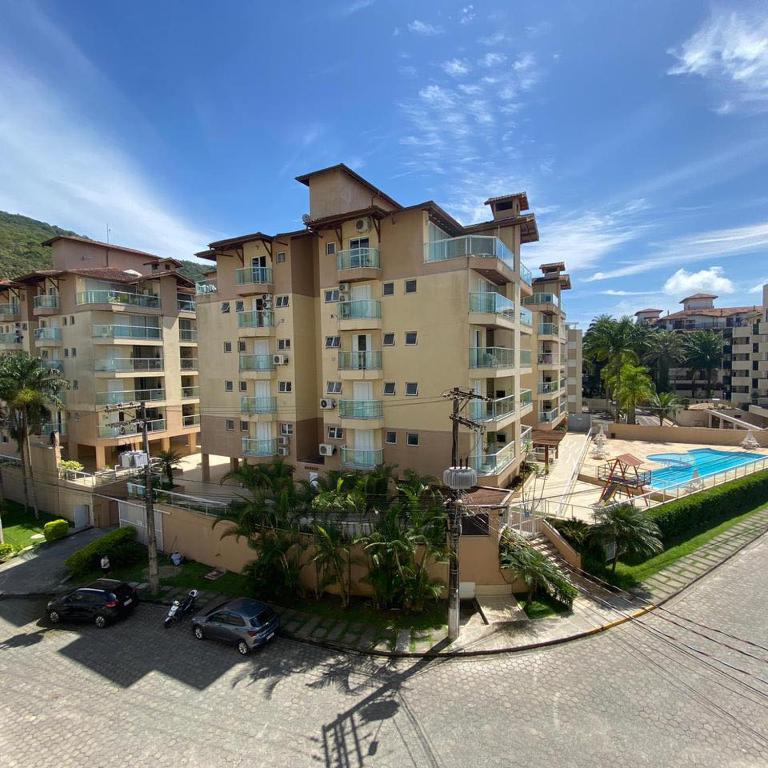 a large apartment building with a swimming pool and parked cars at Apartamento da Martha in Ubatuba