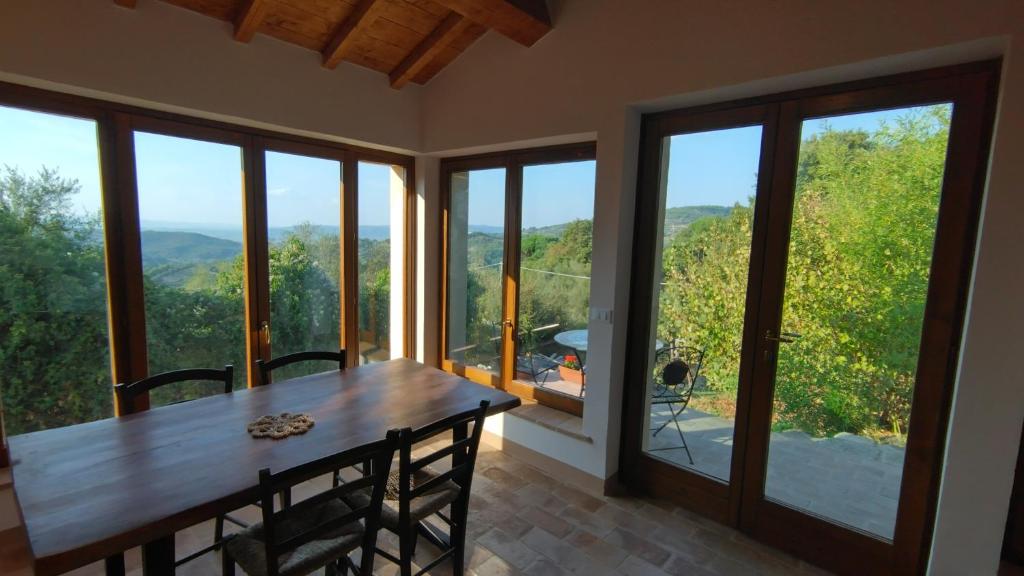 ein Esszimmer mit einem Tisch und großen Fenstern in der Unterkunft Podere Cerrete - Eco Farmhouse in Castel del Piano