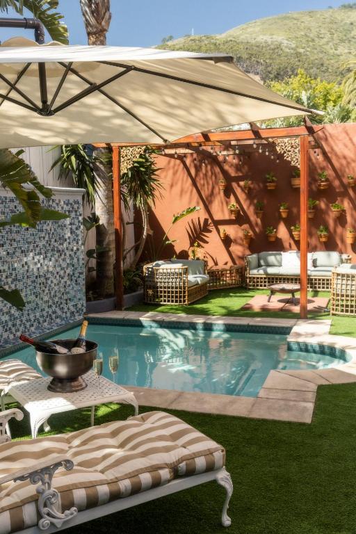 a swimming pool with an umbrella and a table at Sweet Orange Guest House in Cape Town