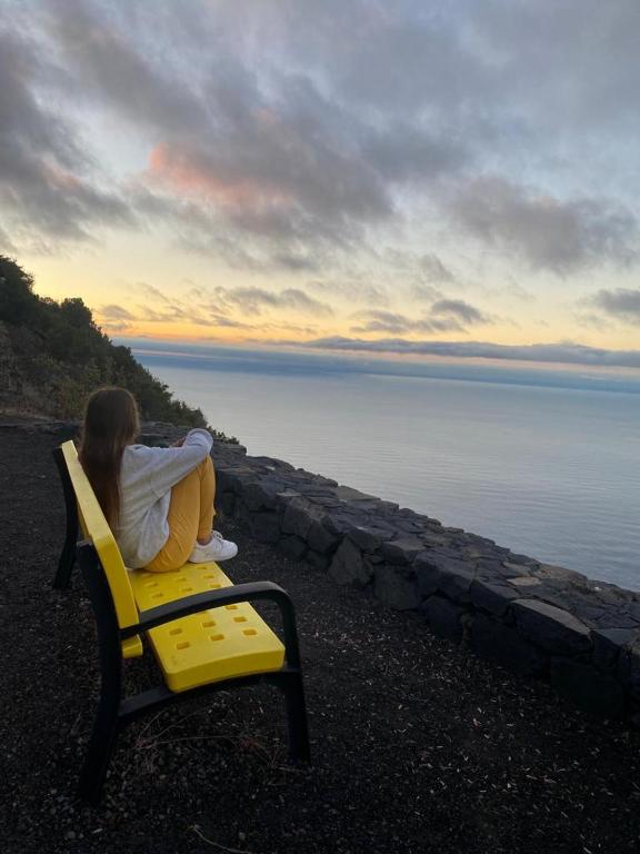 a woman sitting on a yellow chair looking at the water at La Lunita in Valverde