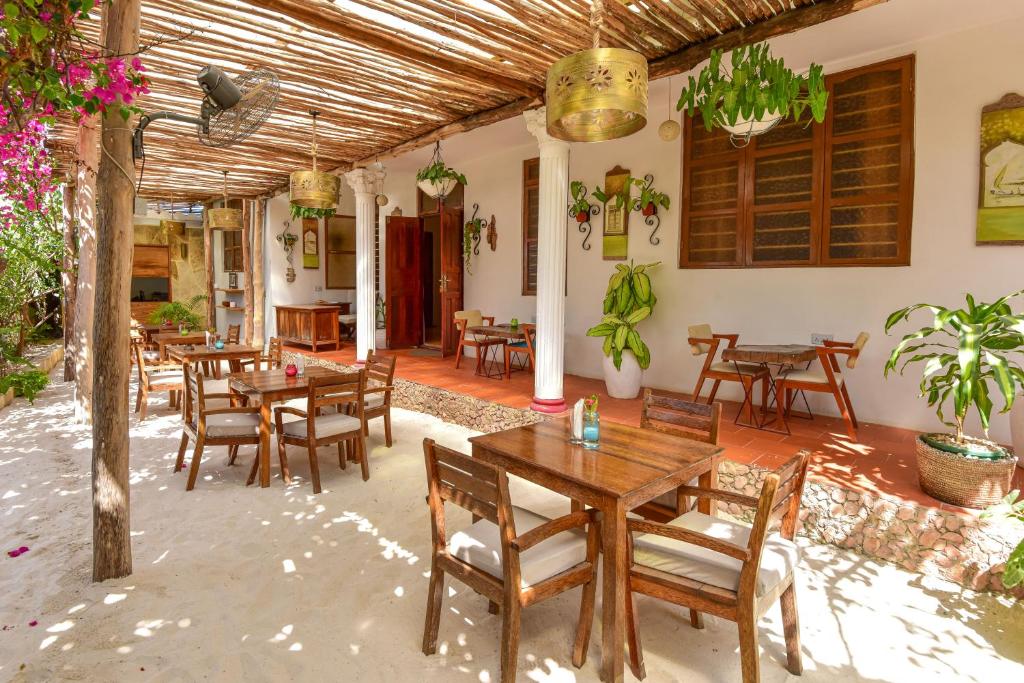 un restaurante con mesas de madera, sillas y plantas en Barabara house en Jambiani