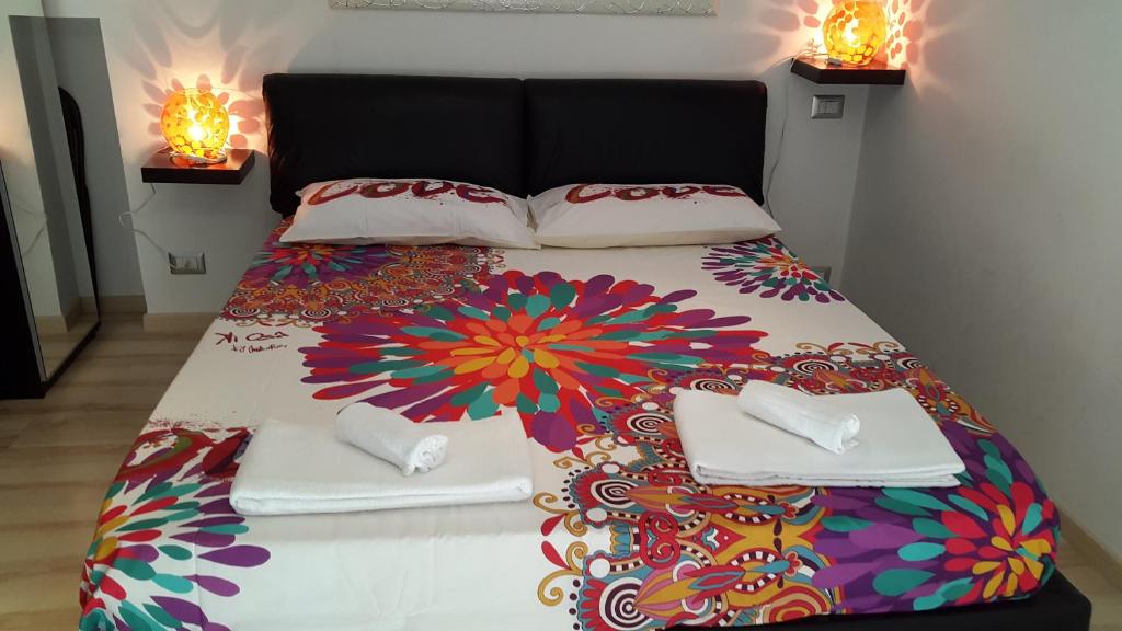 una cama con un edredón colorido y almohadas en ella en La Casa di Gaia - Casa Vacanze a Roma Ottavia, en Roma