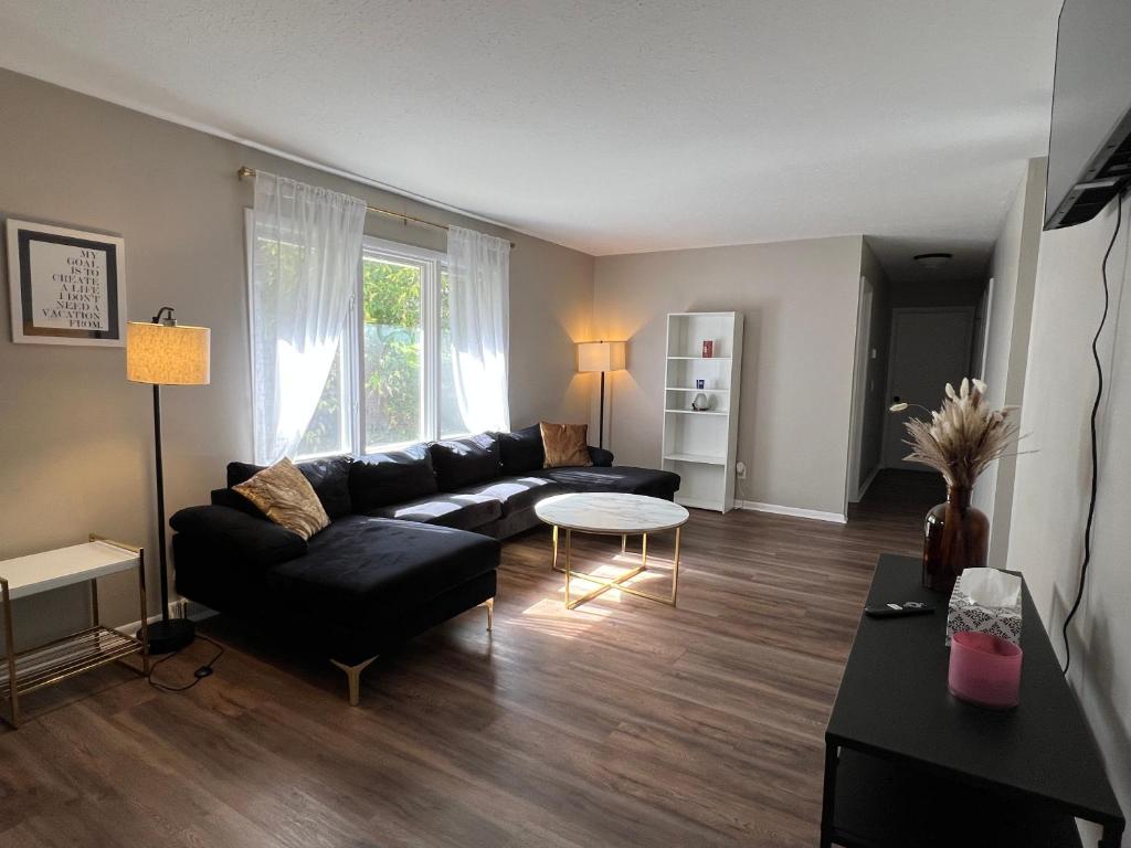 ein Wohnzimmer mit einem schwarzen Sofa und einem Tisch in der Unterkunft Oasis Of Maple Grove in Maple Grove