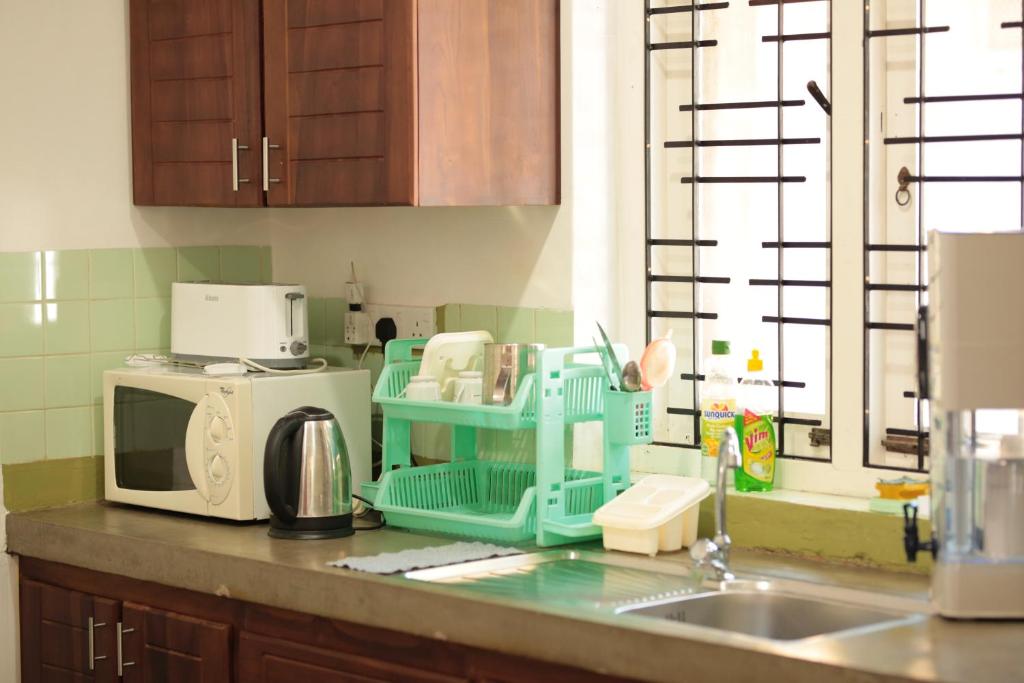 a kitchen counter with a sink and a microwave at Rhome Home in Weligama