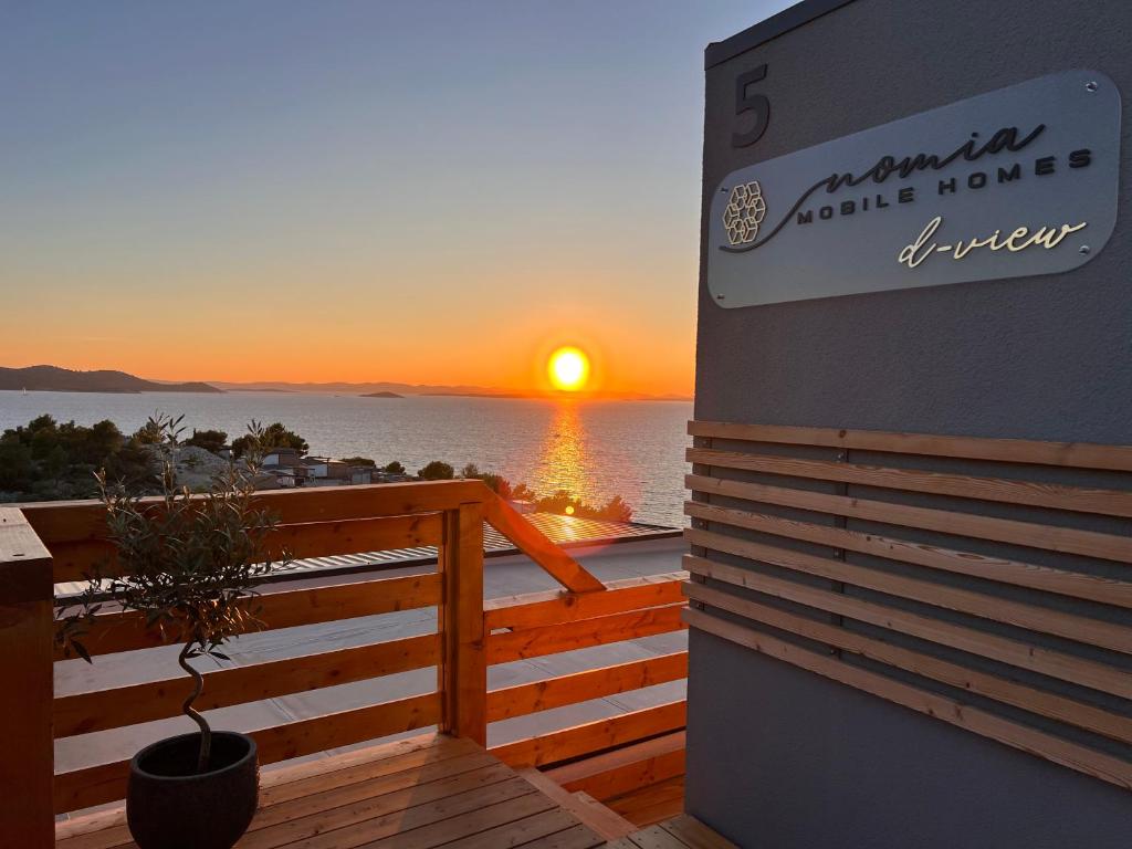 d-view Premium Mobile Home - panoramic seaview - 150 m from beach, free parking في دراغ: غروب الشمس على المحيط مع وجود علامة على منزل جناح مارينا