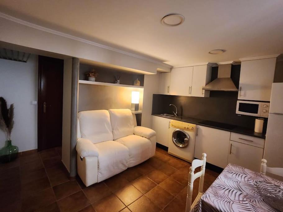 a living room with a white chair and a kitchen at El Apartamento in Ateca