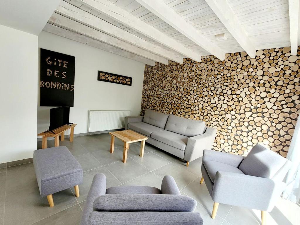 ein Wohnzimmer mit Sofas und eine Wand mit Holzscheiten in der Unterkunft Gîte des Rondins in Aumontzey