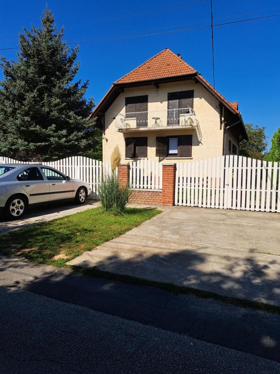 una casa con una valla blanca y un coche en Apartment Oase, en Balatonszemes