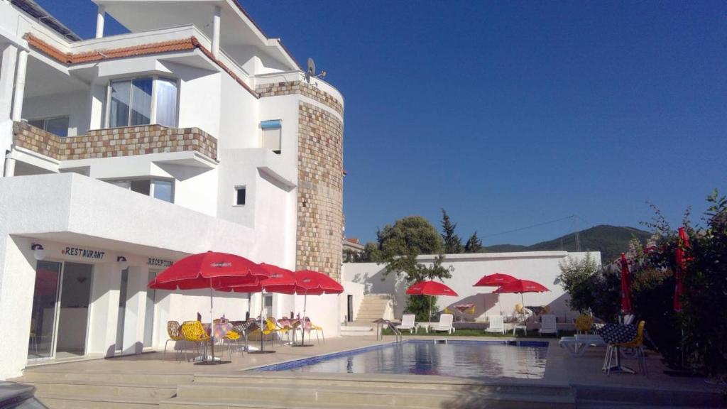 ein Gebäude mit einem Pool mit roten Sonnenschirmen und Stühlen in der Unterkunft NN Residence Tabarka in Tabarca