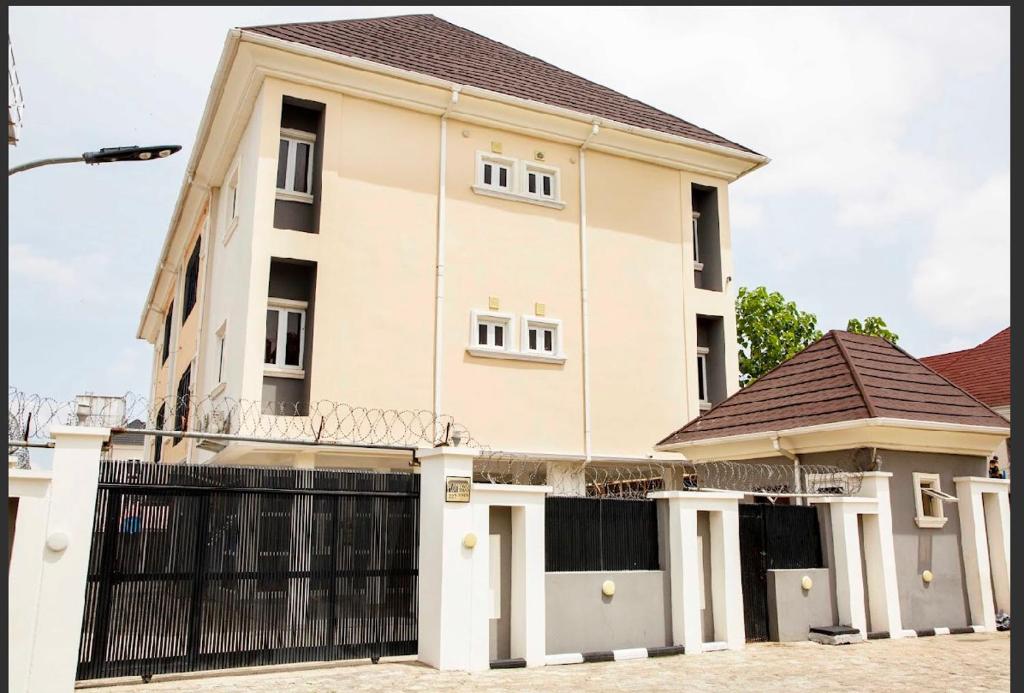 a large white house with a black gate at Duke Diamonds Apartments in Abuja