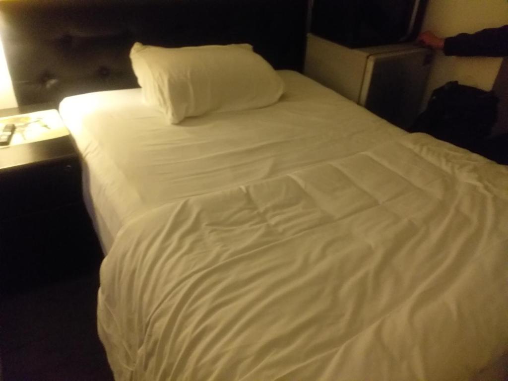 een groot wit bed in een hotelkamer bij A.B.C ROOM SERVICES in Garges-lès-Gonesse