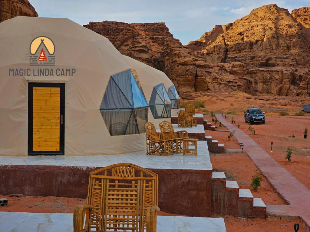 a large tent with chairs and a car parked in the desert at wadi rum,Linda Camp in Wadi Rum