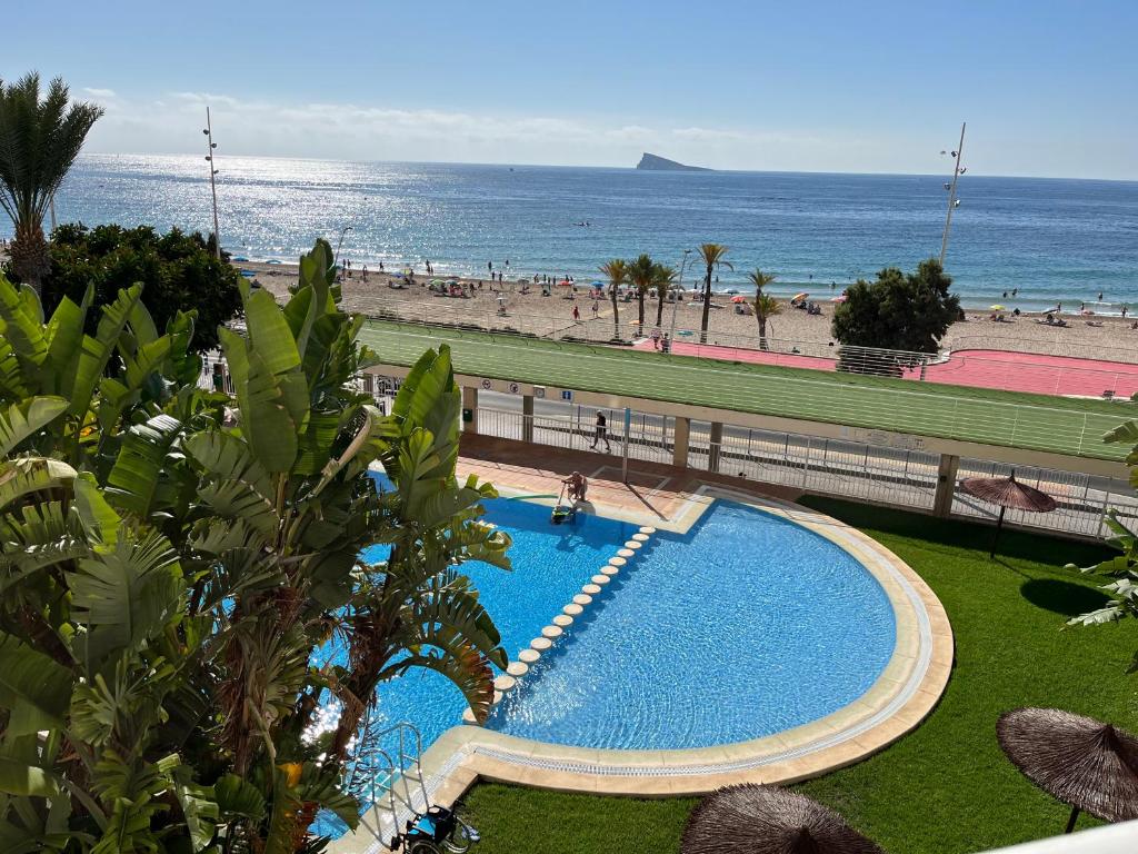 ein Pool neben einem Strand und dem Meer in der Unterkunft Precioso apartamento en 1º Línea de playa in Benidorm