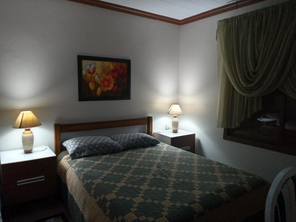 a bedroom with a bed with two night stands and two lamps at CASA DA FAMÍLIA DE GRAMADO in Gramado