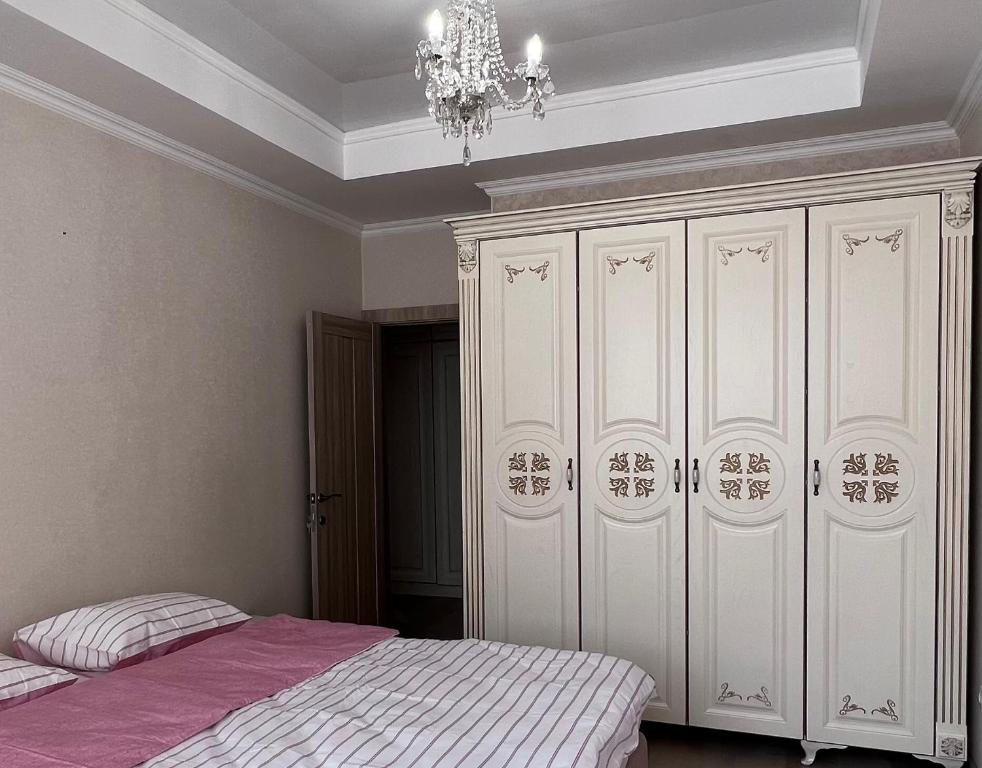 a bedroom with a bed and a large white cabinet at Абрикос in Bishkek