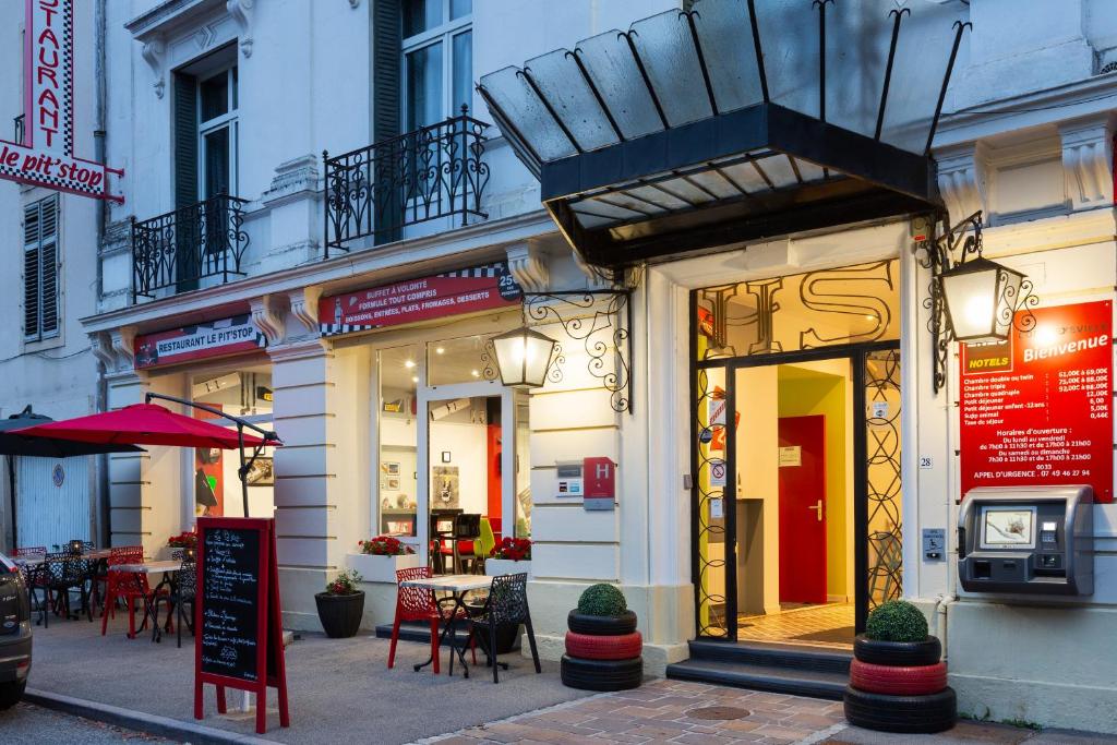 a store front with tables and chairs on a city street at Enzo Hotels Contrexeville by Kyriad Direct in Contrexéville