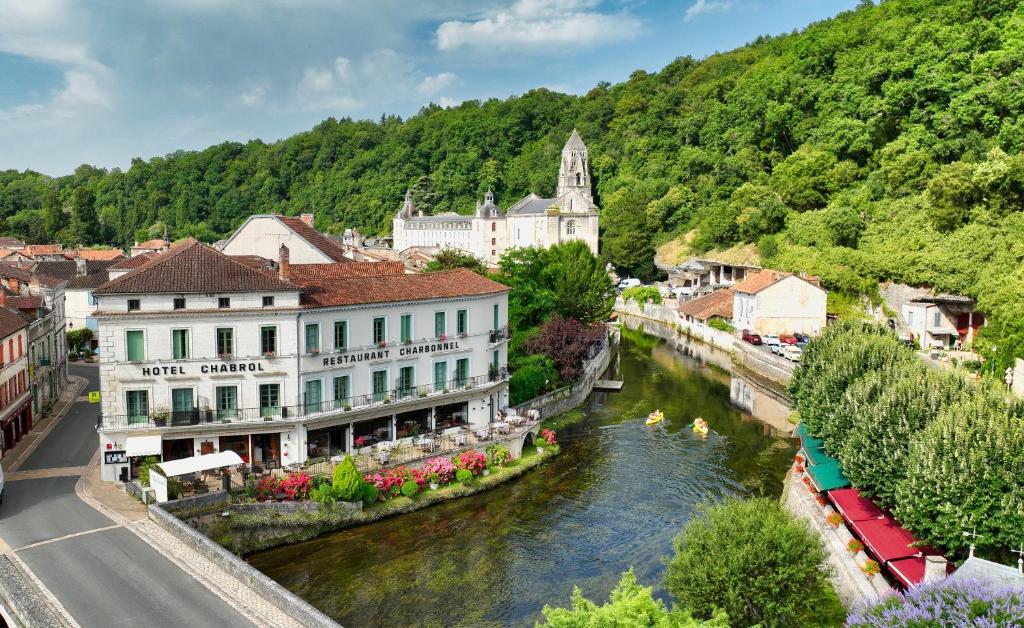 eine Stadt mit einem Fluss und Gebäuden neben einem Berg in der Unterkunft Hotel Restaurant Charbonnel in Brantôme