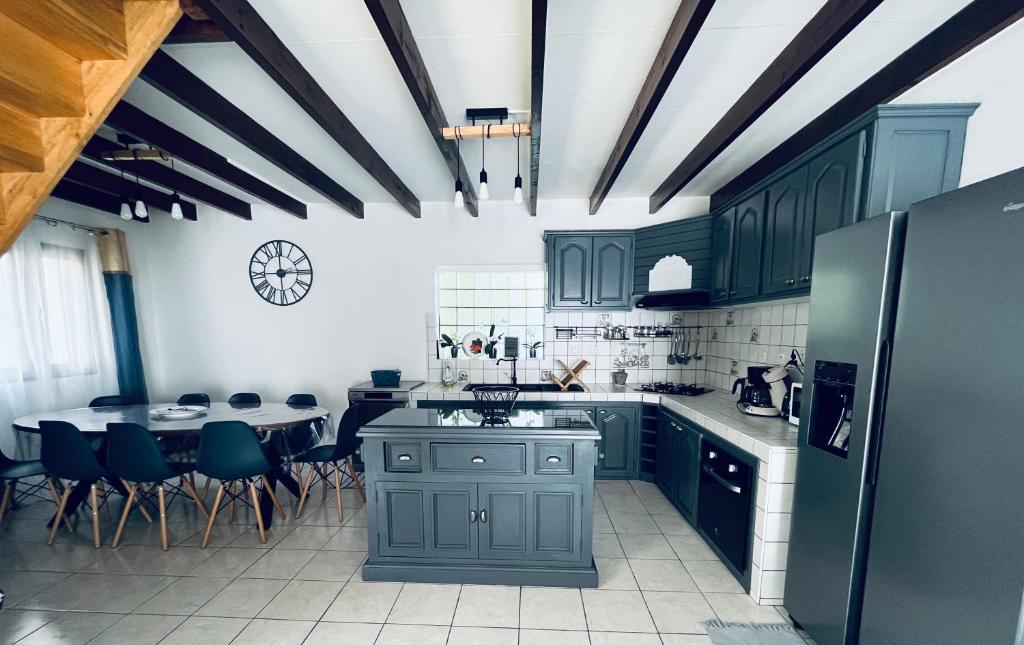 a kitchen with green cabinets and a table with chairs at Villa Longani Passion pour des vacances bucoliques en famille in Petite Île