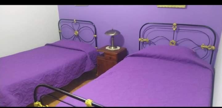 a purple bedroom with two beds and a table at Posada del Abuelo in Torotoro