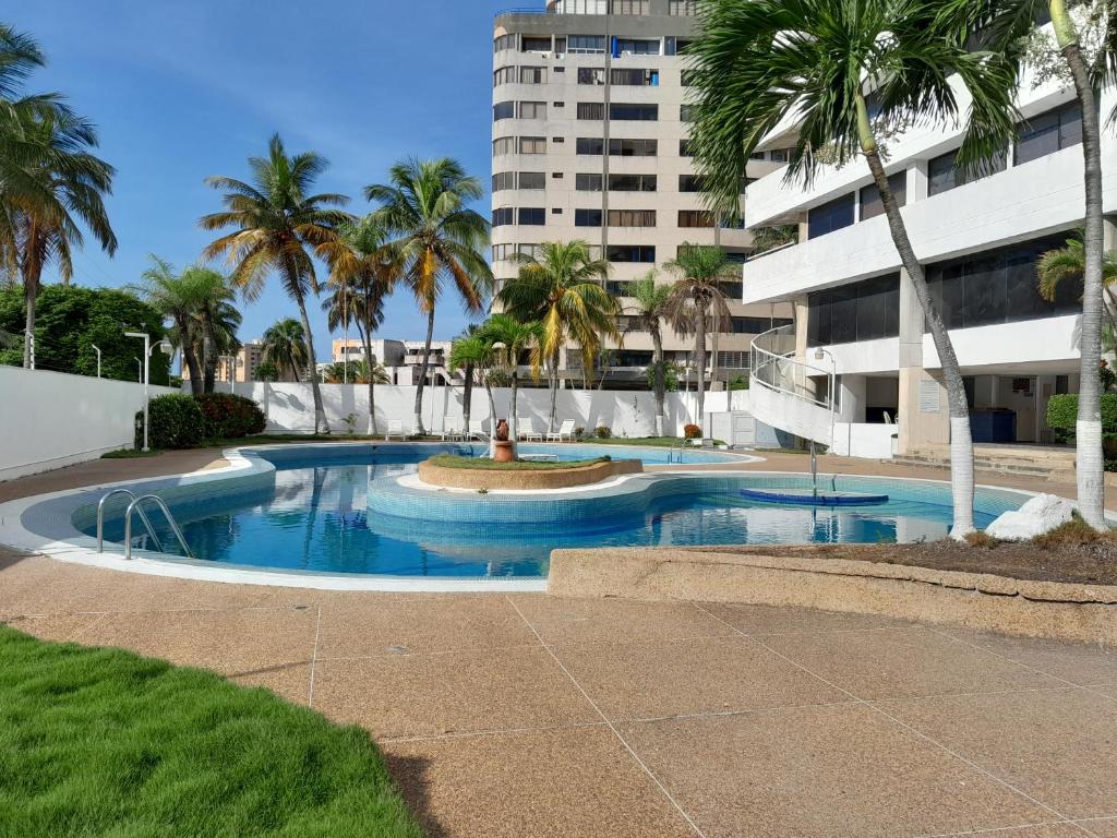 a swimming pool with a fountain in front of a building at Executive Style Condo With Sea Views in Porlamar