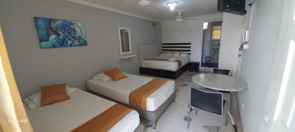 Habitación con 2 camas, mesa y escritorio. en HOSTAL PARMA, en Santa Marta
