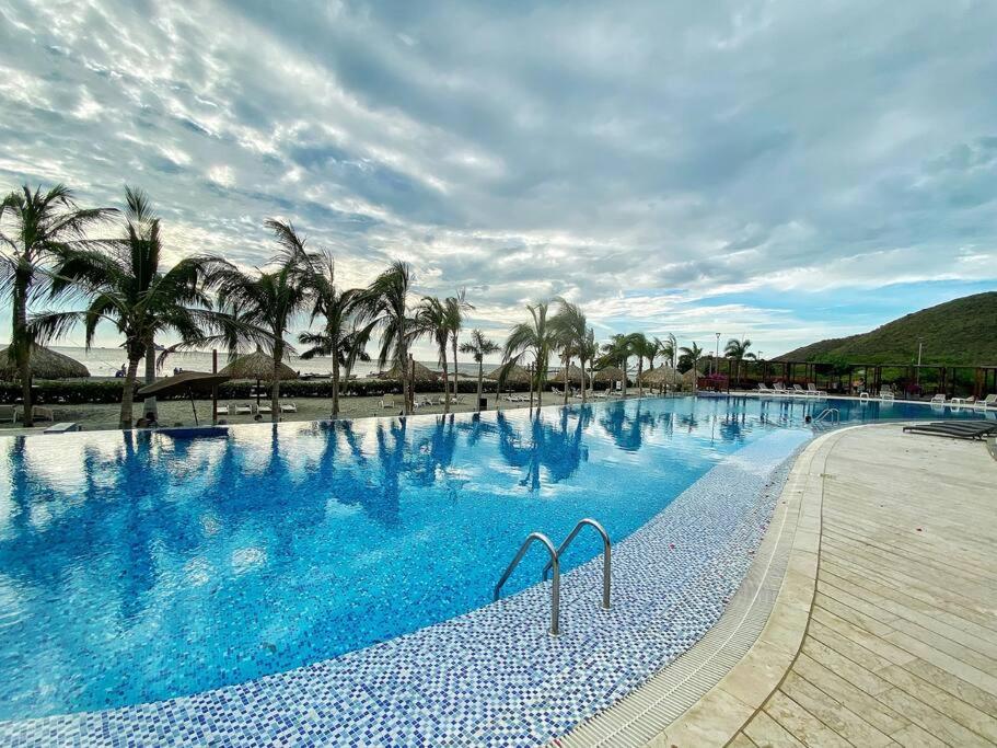 uma grande piscina com palmeiras numa praia em Sensacional apartamento en Samaria Club de Playa em Santa Marta