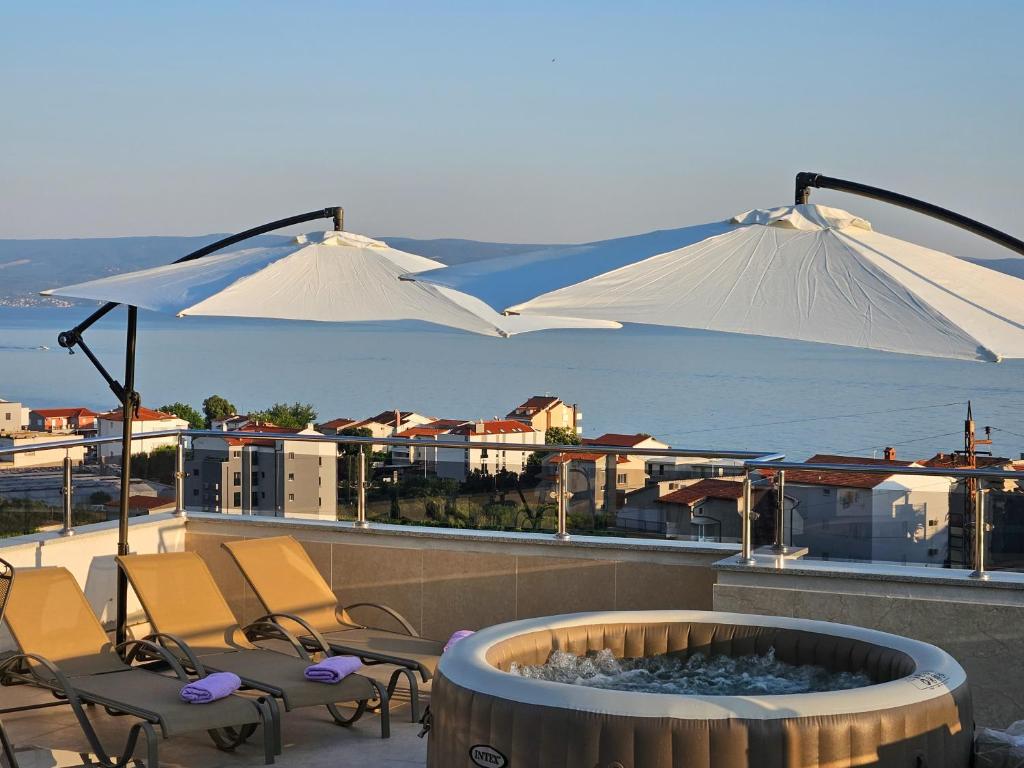 zwei weiße Regenschirme über einer Feuerstelle auf einem Balkon in der Unterkunft Modern villa with jacuzzi, beautiful sea view, near Split! Villa 36A in Podstrana