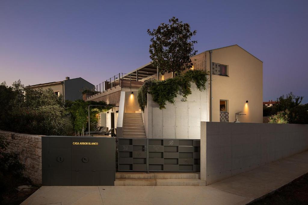 uma casa com uma escada em frente em Casa Arbor Blanco with a see view and heated infinity pool em Fažana