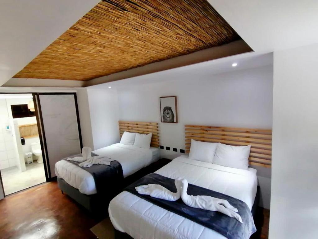 a bedroom with two beds with white sheets at Ávita Lodge in Quesada