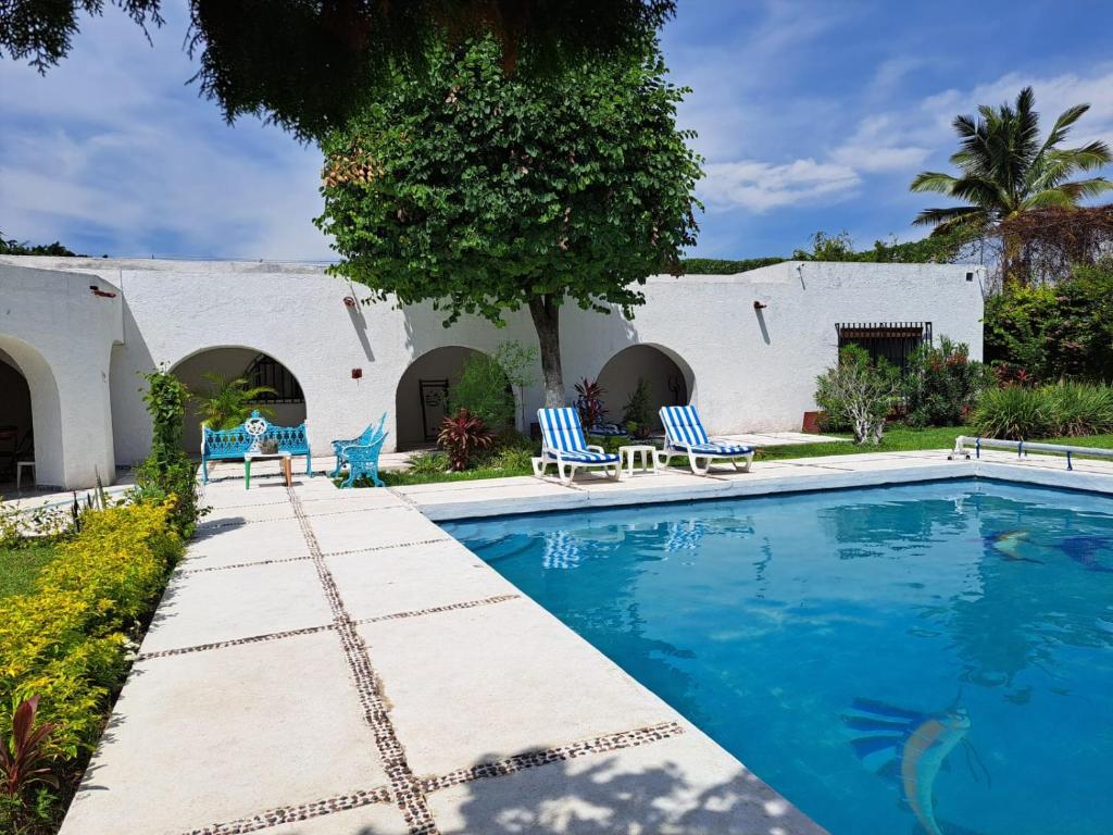 Quinta Lachaud في Chiconcuac: مسبح وكراسي زرقاء بجانب مبنى