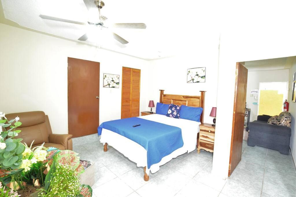 a bedroom with a bed with a blue blanket and a couch at Cozy Locale Pearl in Port Antonio