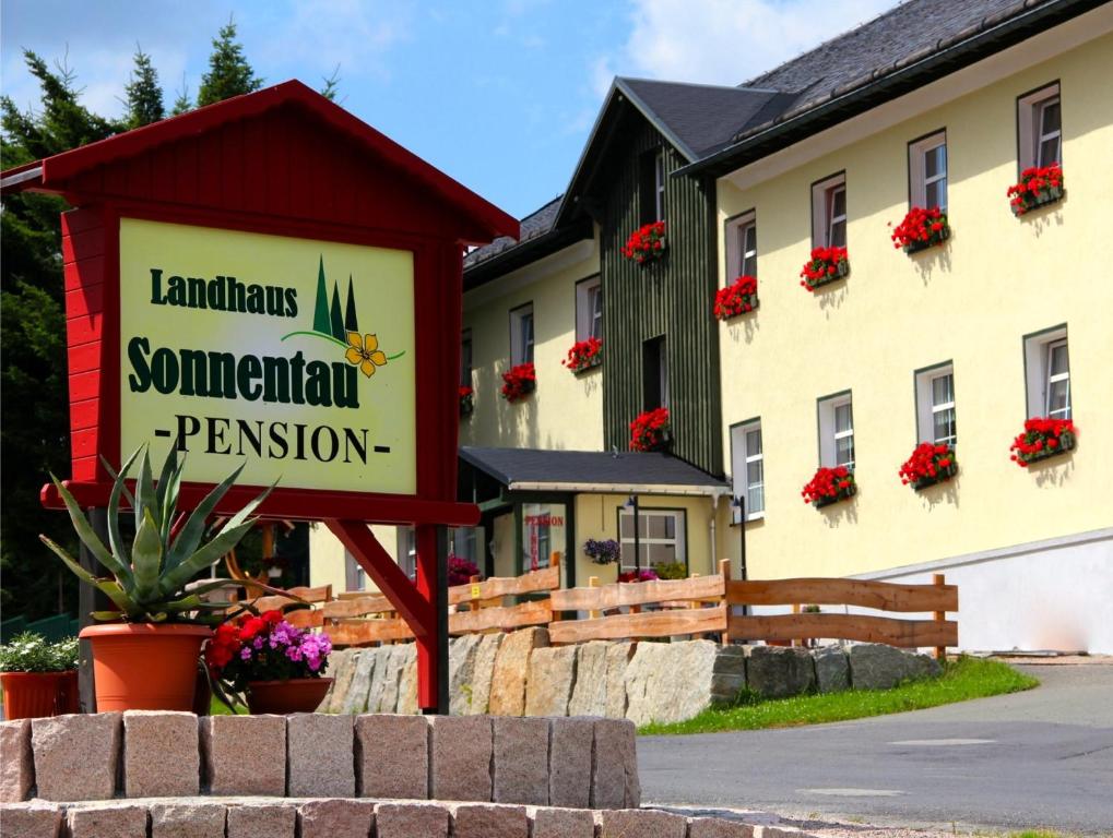 a sign in front of a building with flowers at Landhaus Sonnentau in Johanngeorgenstadt