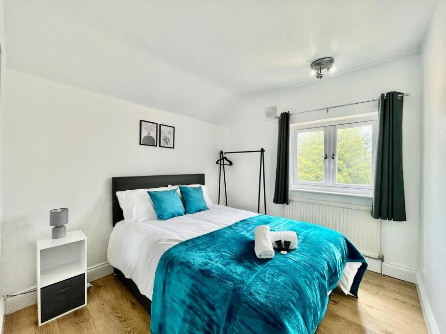 a bedroom with a bed with a blue blanket on it at Contractor Leisure Stay in Romford - Free Parking in Havering atte Bower