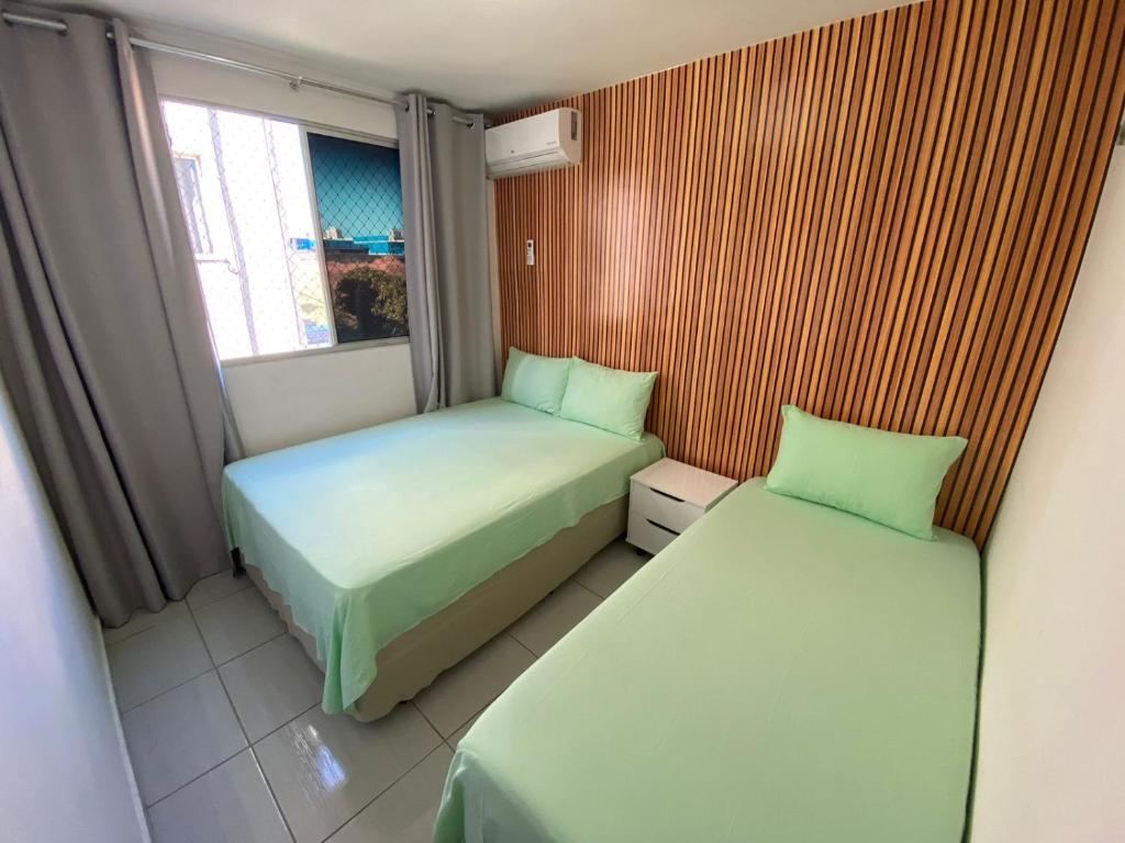 2 Betten in einem kleinen Zimmer mit Fenster in der Unterkunft Apartamento na Grande Natal (Condomínio Barcas) in Natal