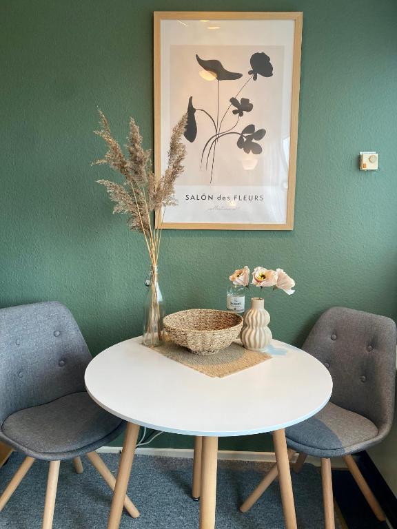 a table with two chairs and a vase on it at Ferienwohnung Meernähe in Fehmarn
