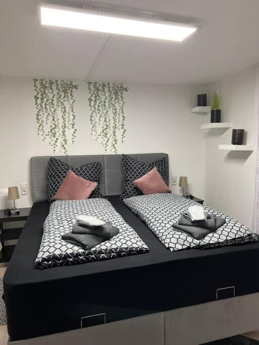 Una cama blanca y negra con almohadas rosas. en SaLiMu Ferienwohnung, en Tettnang